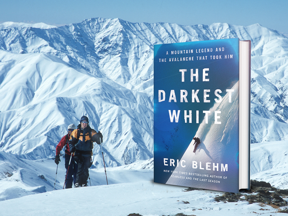 In the background, two men ski upslope toward the camera. Large snow-covered mountains loom behind them. A book with the title 'The Darkest White' is superimposed on the foreground.