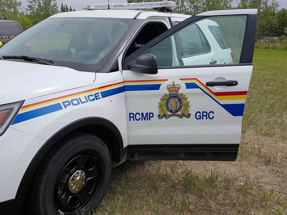 A white sport utility vehicle is parked on a grassy field with the driver’s-side door open. It is adorned with the blue, red and yellow decals of the Royal Canadian Mounted Police.