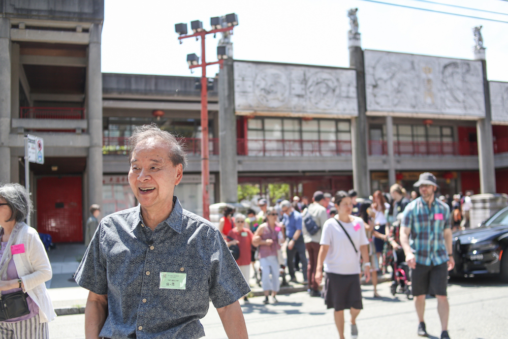An ethnically Chinese man in a short-sleeve button-up crosses the street in Vancouver’s Chinatown, with a crowd behind him.