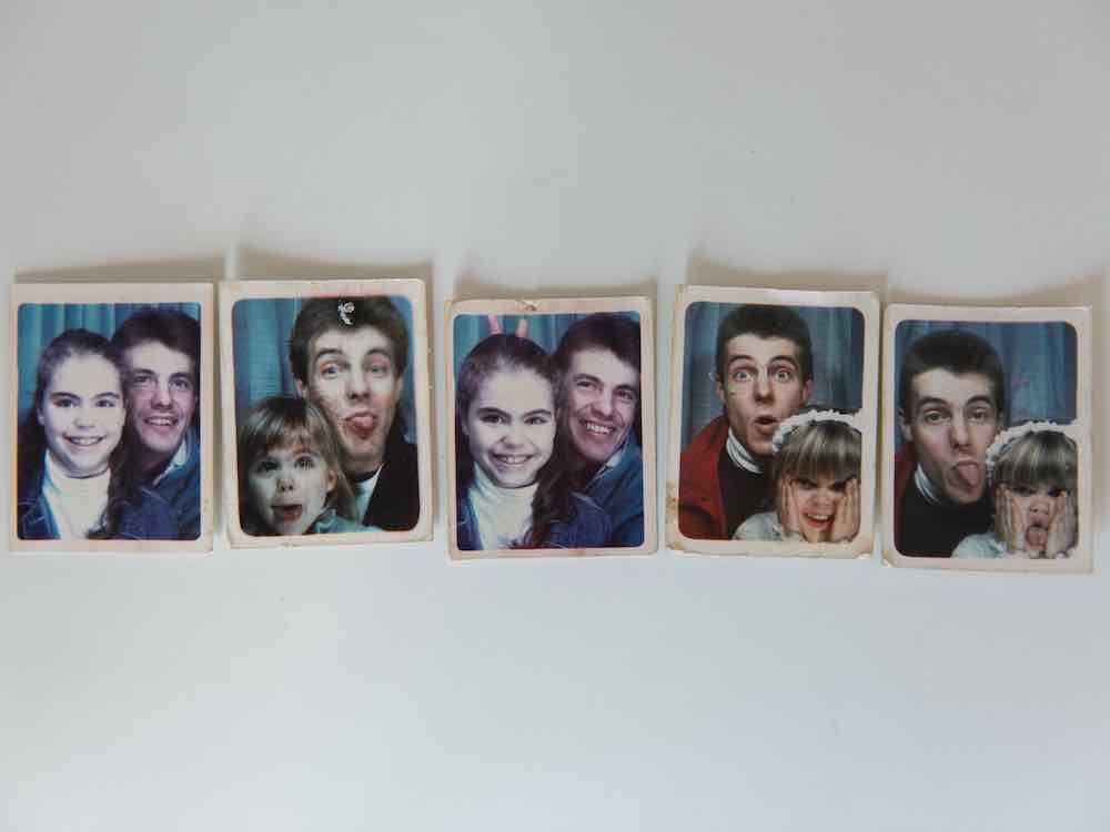 Five pocket-sized colour photos in the style of those found in a shopping mall photo booth are arranged horizontally across a white background. They depict a young girl with light skin and dirty blond hair with her father, a young man with light skin and brown hair, against blue curtains. They are playfully experimenting with a range of facial expressions for the camera.