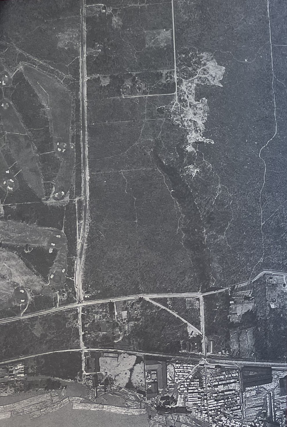 A black and white aerial photograph of a large tract of open land. At the bottom right is a cluster of buildings. There is a large ravine that goes right through the area where Everett Crowley Park now sits.