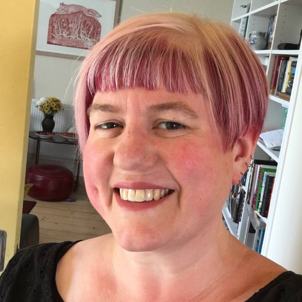 A woman with short salt and pepper hair smiles at the camera.