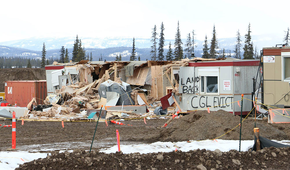 Heavily damaged trailers and port-o-johns on a worksite. There is some snow on the ground.