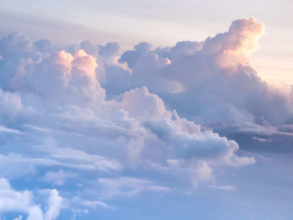 A bright crop of fluffy clouds at sunset against a blue sky.