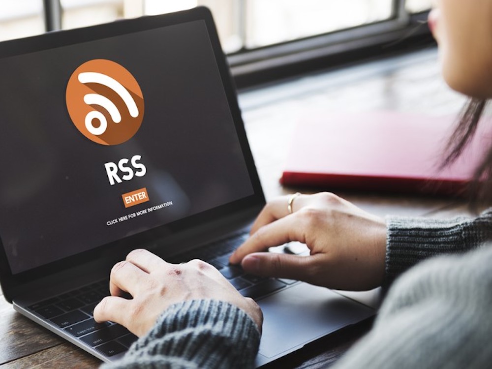 A woman types into a computer. The words RSS are on the screen. 
