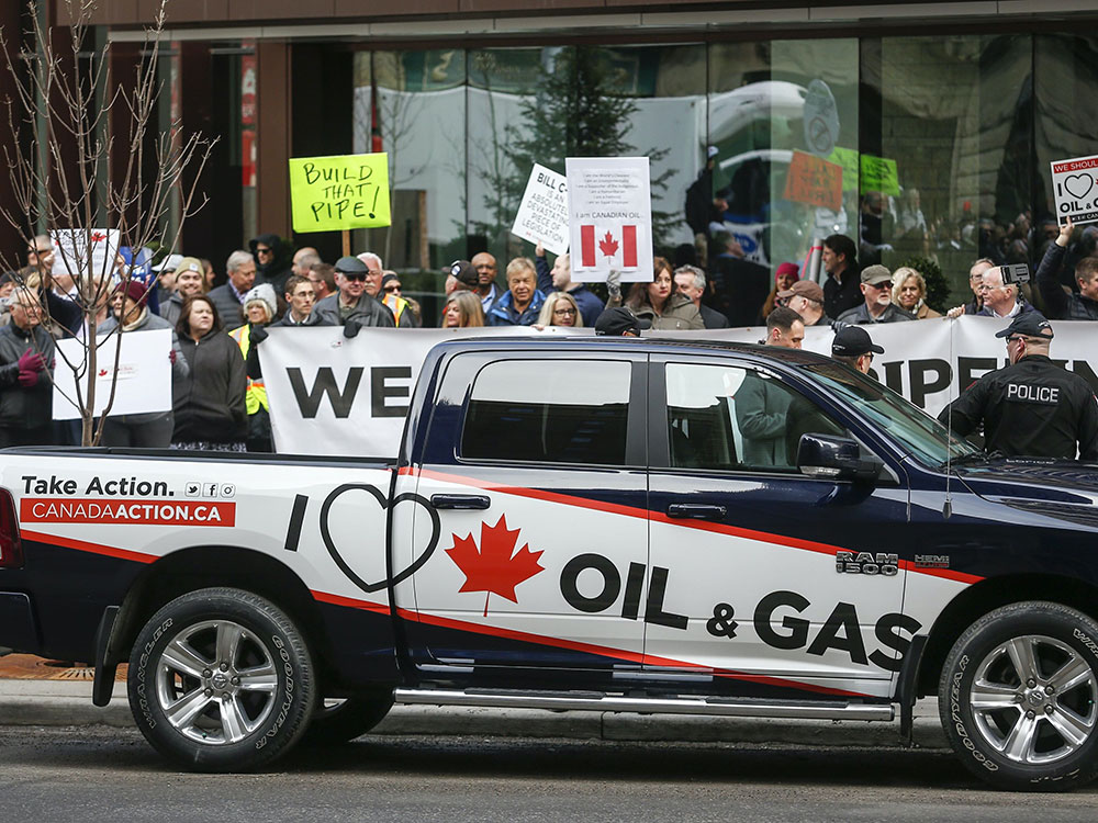A black-and-white truck bears the slogan &ldquo;I love Canadian oil and gas&rdquo; as protesters hold signs calling for pipelines to be built.