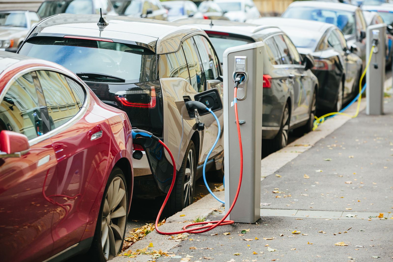 A lineup of electric cars plugged into charging stations.