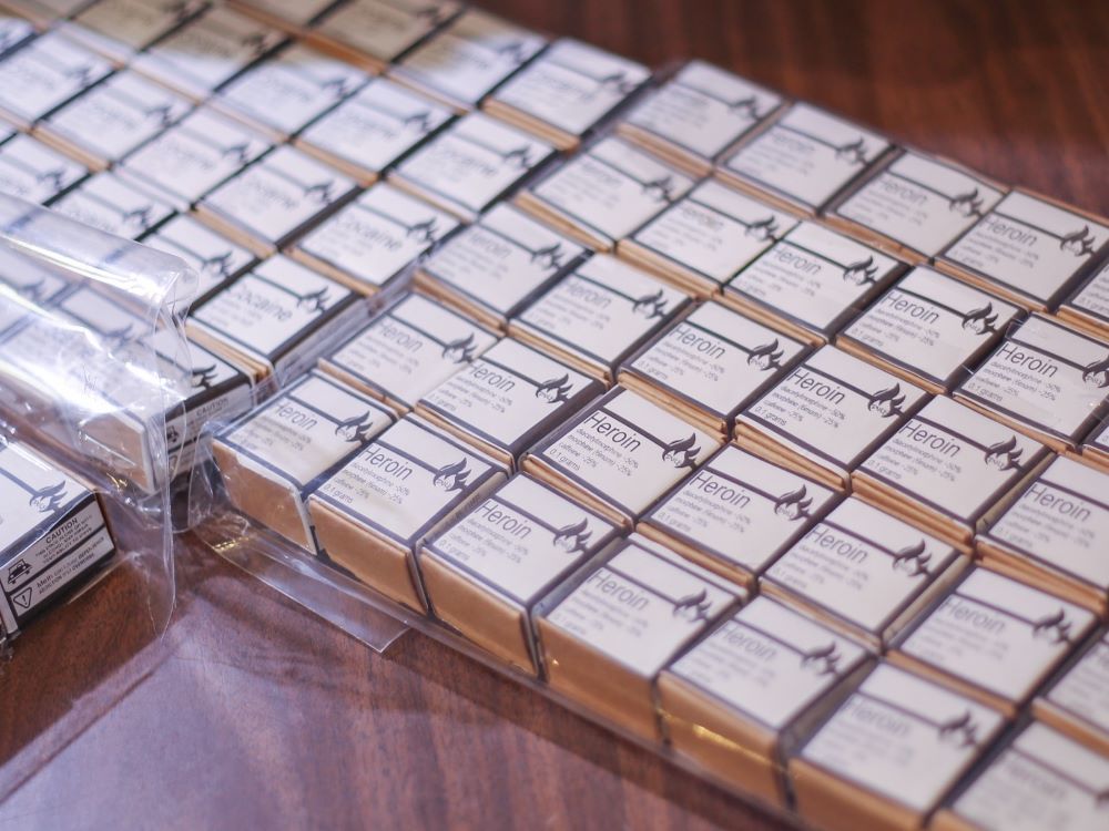 Rows of small boxes labelled heroin sit on a table.
