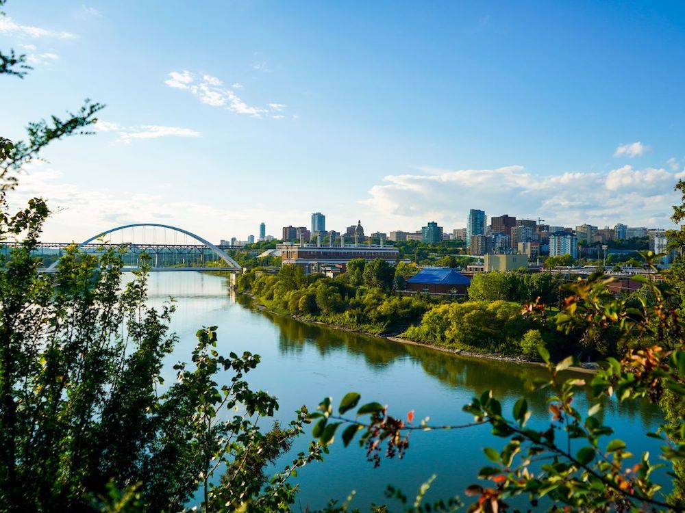 A cityscape viewed from across a river under a blue sky.