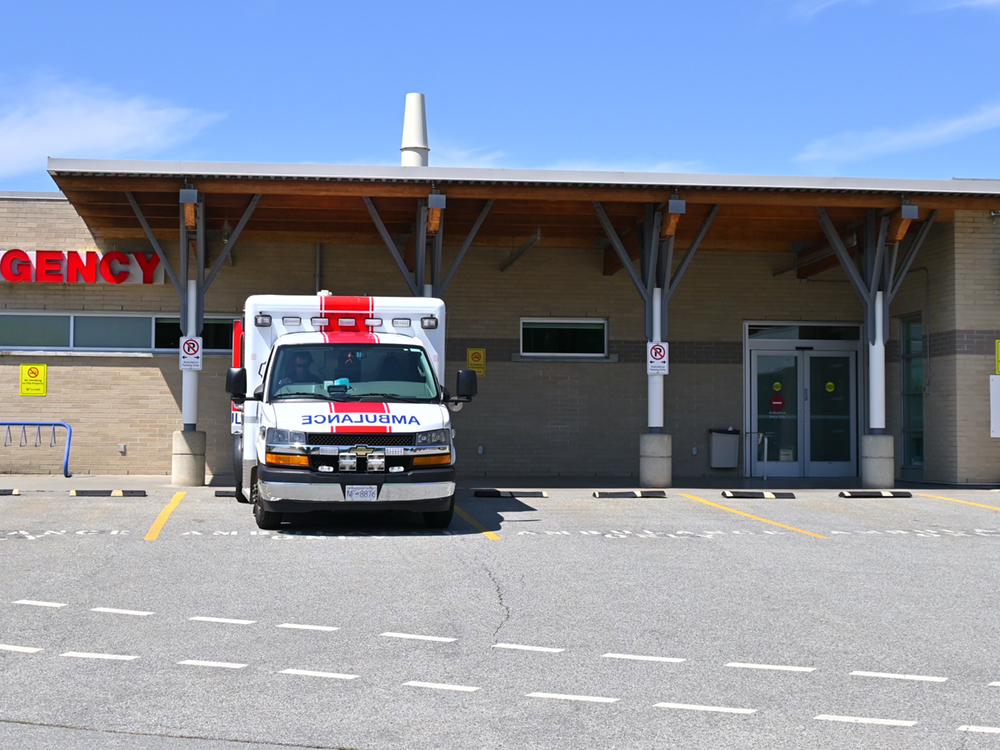 One ambulance is parked in the ambulance bay at the hospital in Delta, B.C. ‘Emergency’ is on the wall in red letters behind the ambulance.