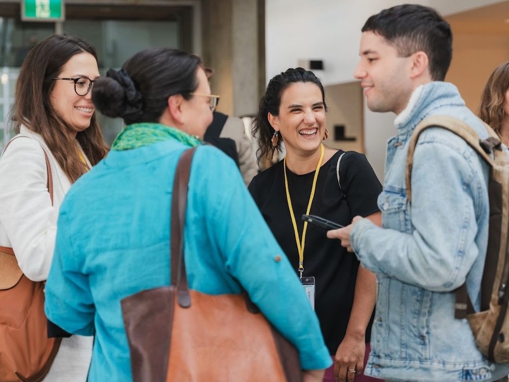 A group of four people stand in a casual circle, chatting and smiling.