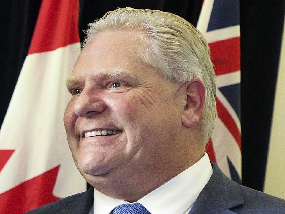 A three-quarter profile of a smiling light-skinned man with short platinum-blond hair.