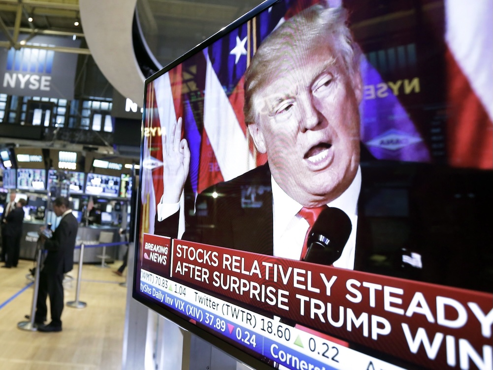 A television screen shows the face of Donald Trump with words underneath: Stock relatively steady after surprise Trump win.