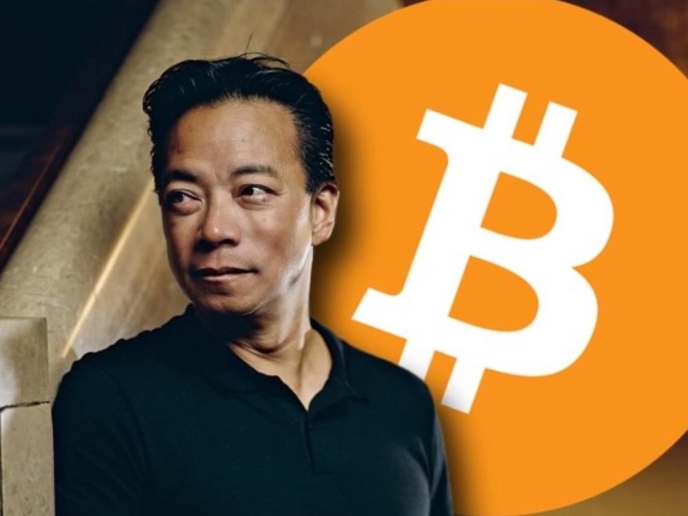 A photo of Ken Sim, a man with medium-light skin tone and short black hair wearing a black shirt, appears next to the round orange Bitcoin logo.