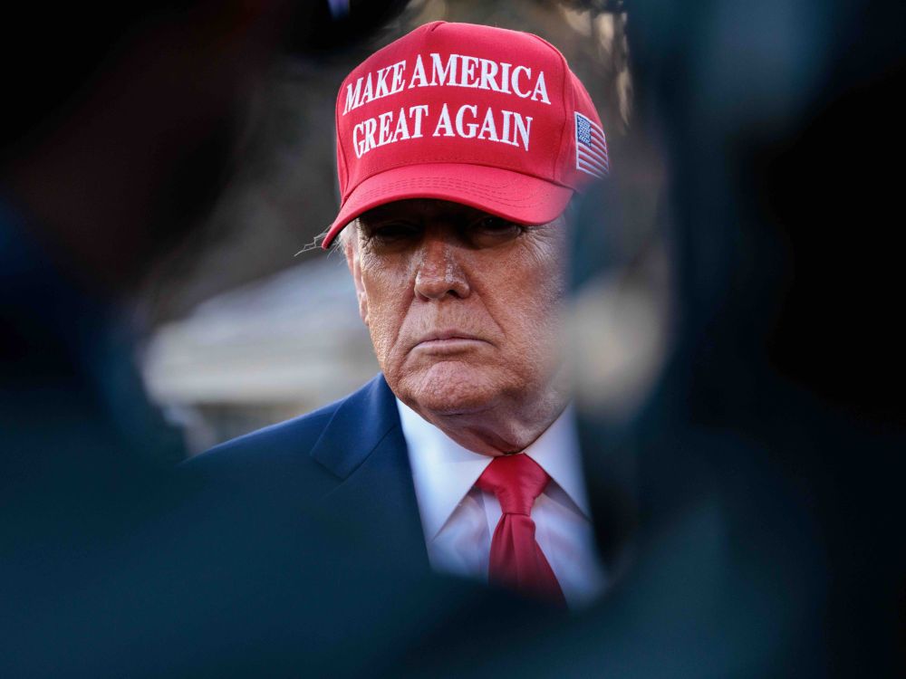 Donald Trump is wearing a suit and red &ldquo;Make America Great Again&rdquo; ball cap.