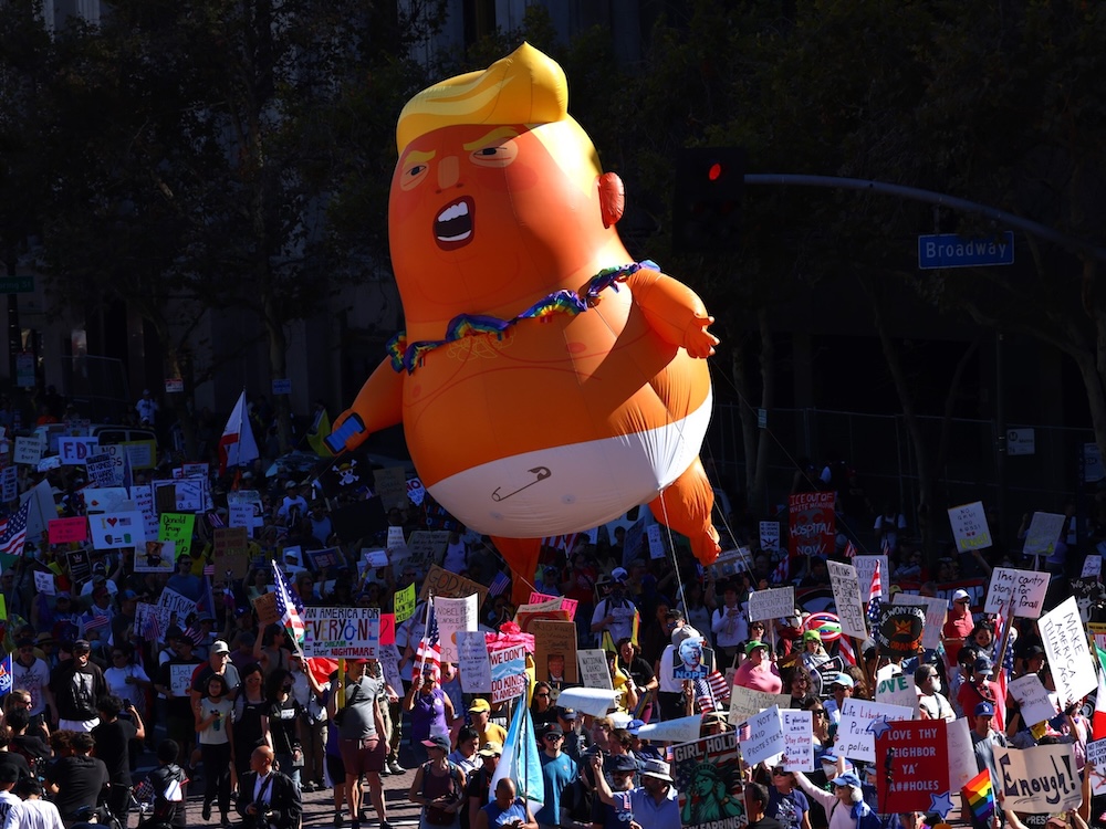Protesters float an inflatable Donald Trump balloon that is very orange, and wearing a diaper.