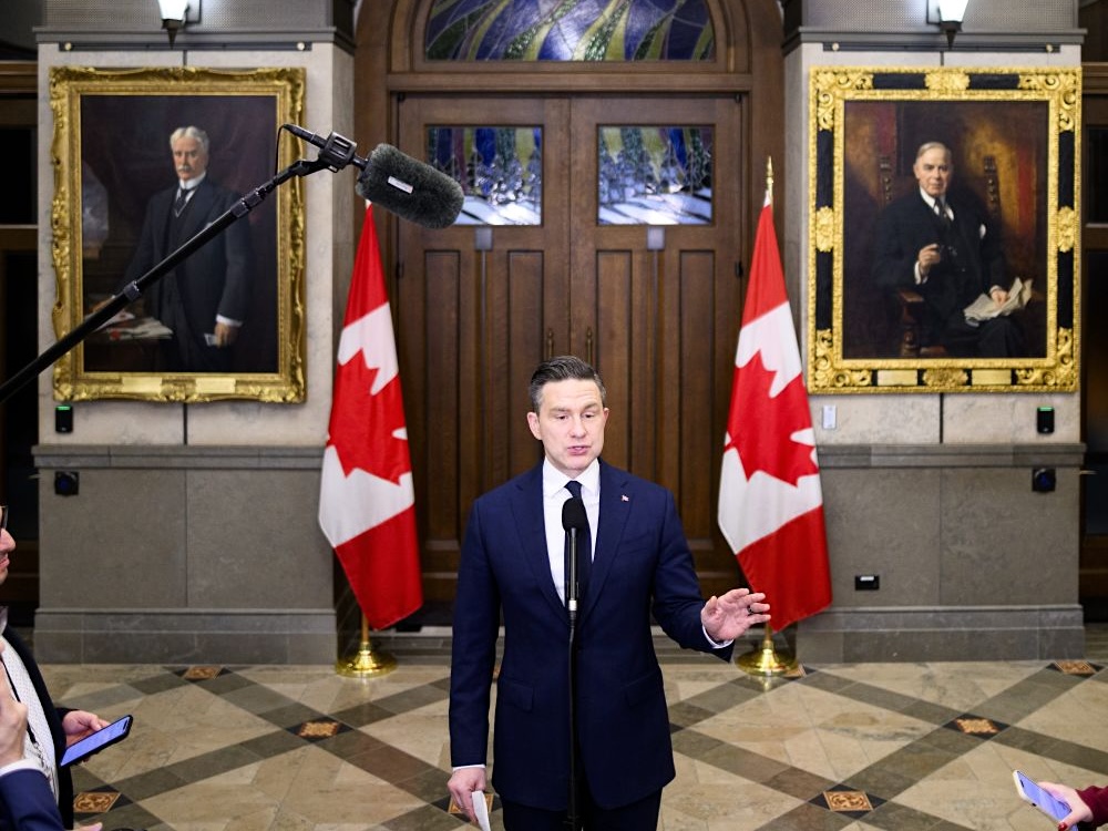 Pierre Poilievre wears a blue suit and addresses media.