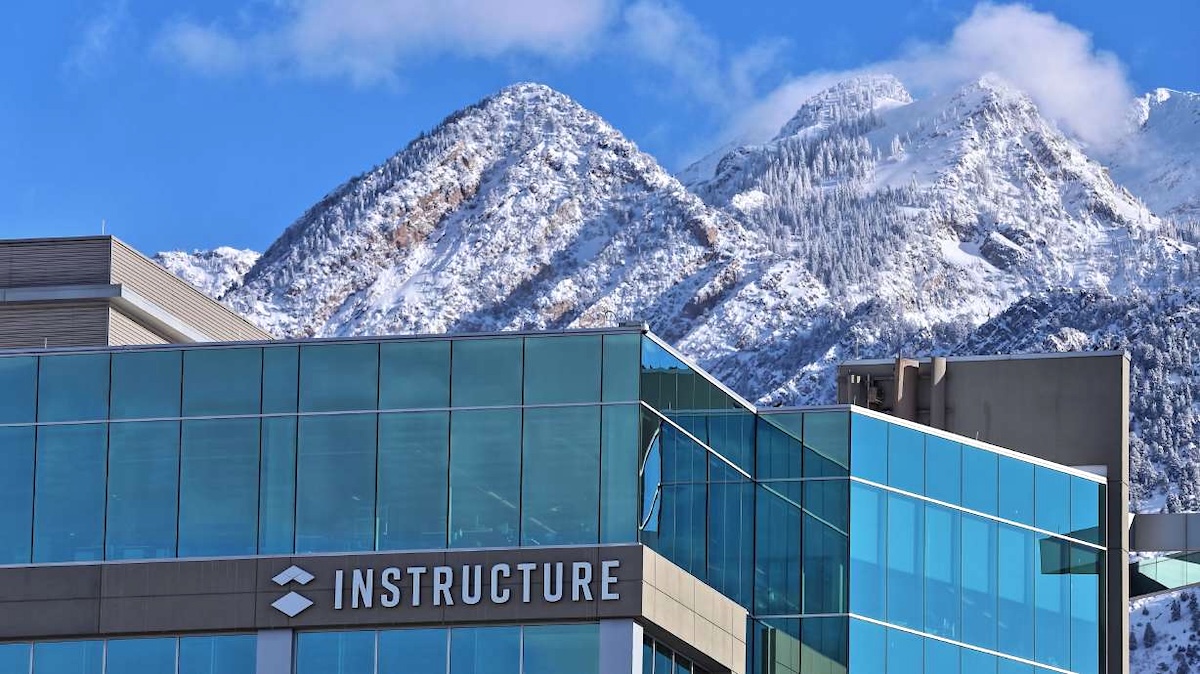 An office building with the name &lsquo;Instructure&rsquo; on a bright clear day with snowy peaks behind it.