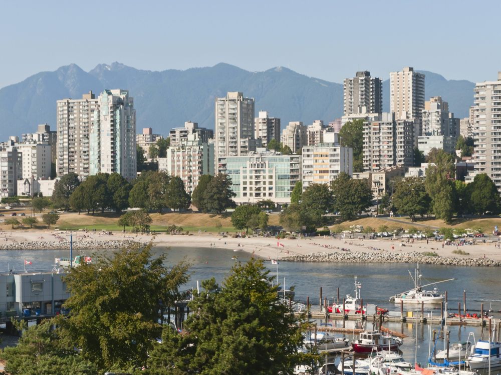West End apartments are seen across a stretch of water and beach, with mountains in the background.