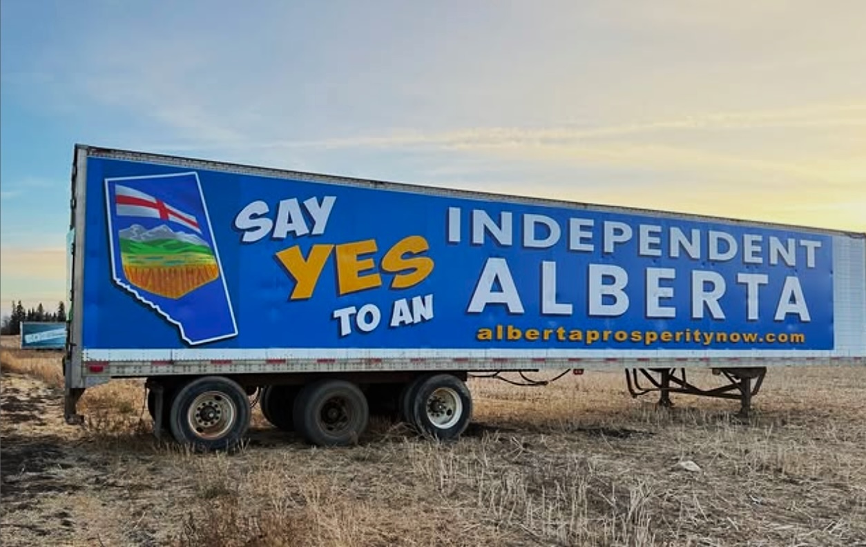 A transport truck trailer parked in a grassy field displays a sign saying &lsquo;Say yes to an independent Alberta.&rsquo;