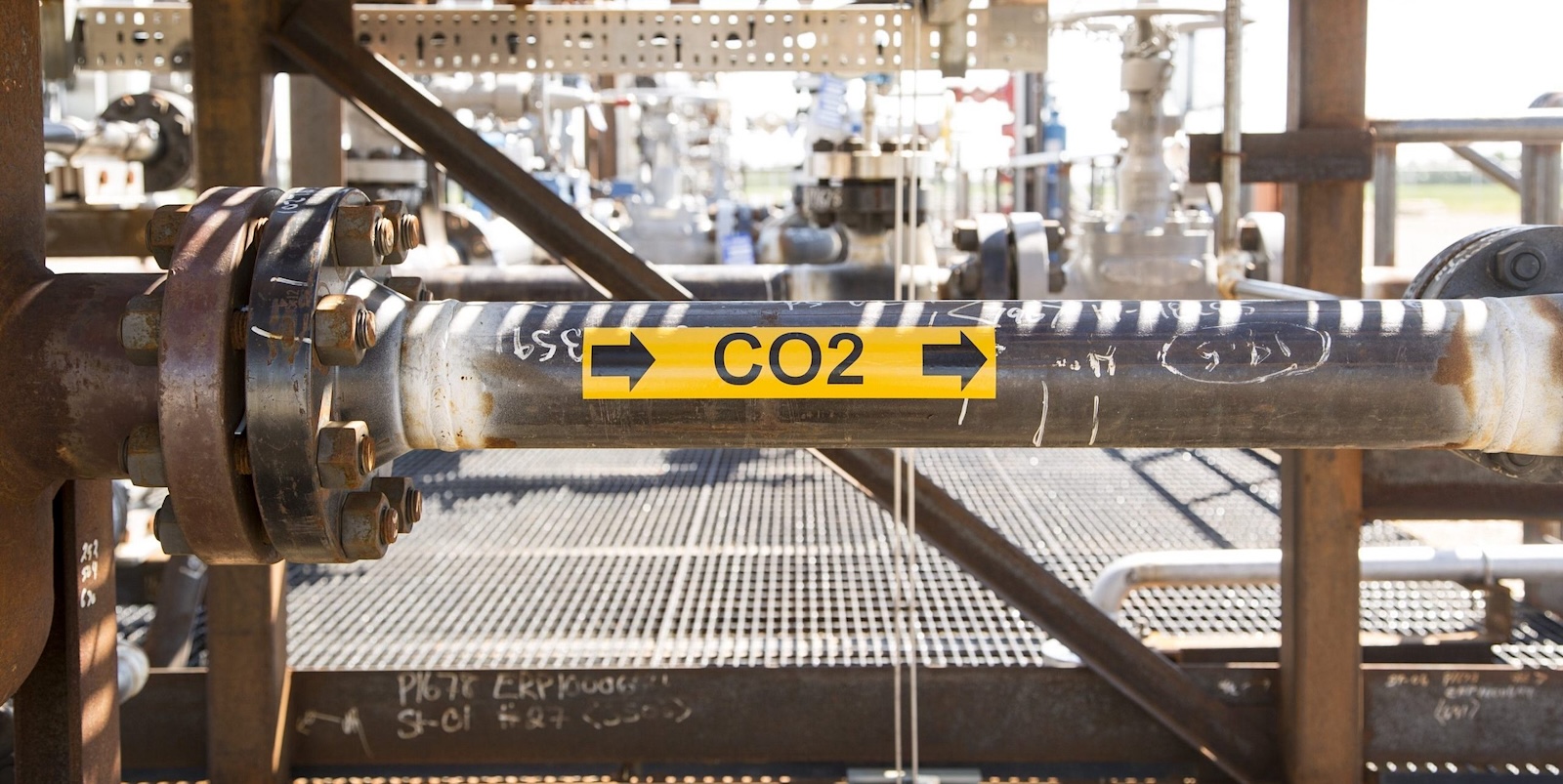 A yellow label marked &lsquo;CO2&rsquo; with arrows pointing to the right is seen on a pipe in an industrial setting.