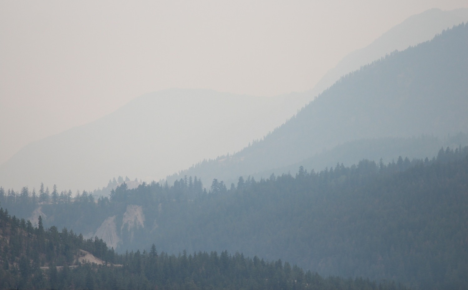 The view of a mountain range is obscured and hazy from wildfire smoke.