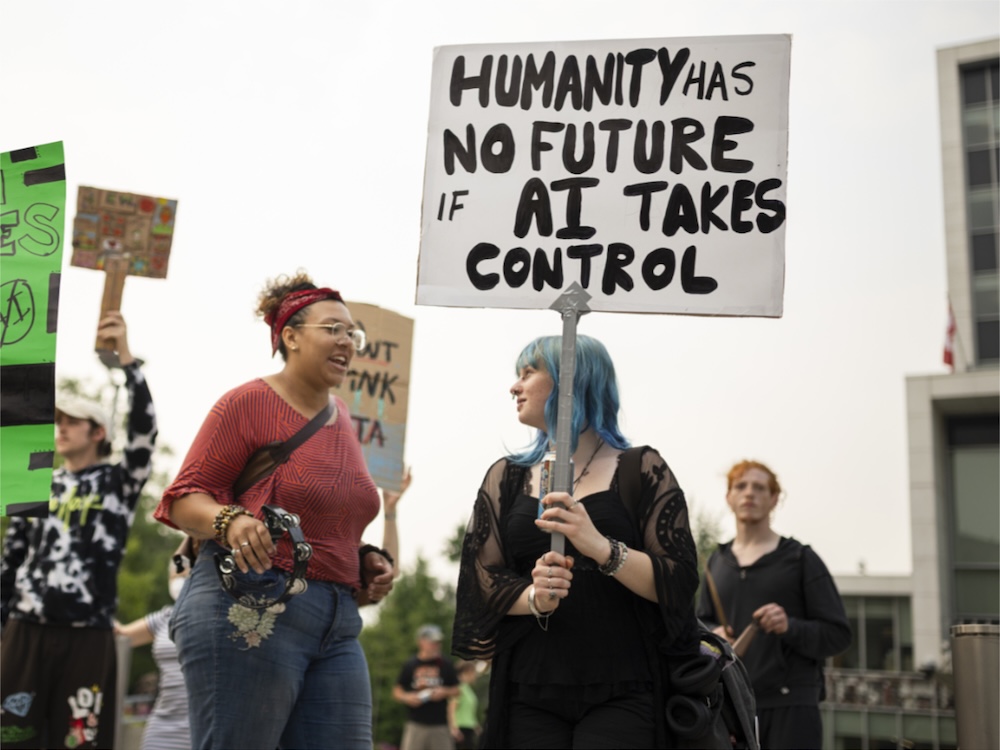 A young woman with blue hair holds a sign that says &lsquo;Humanity has no future if AI takes control.&rsquo;