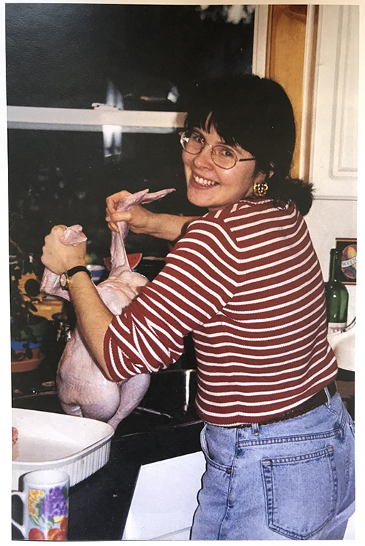 Michelle Gamage&rsquo;s aunt Diana holds a raw turkey over the sink in a photo that appears to have been taken in the late 1990s. She is smiling and looking back at the camera.