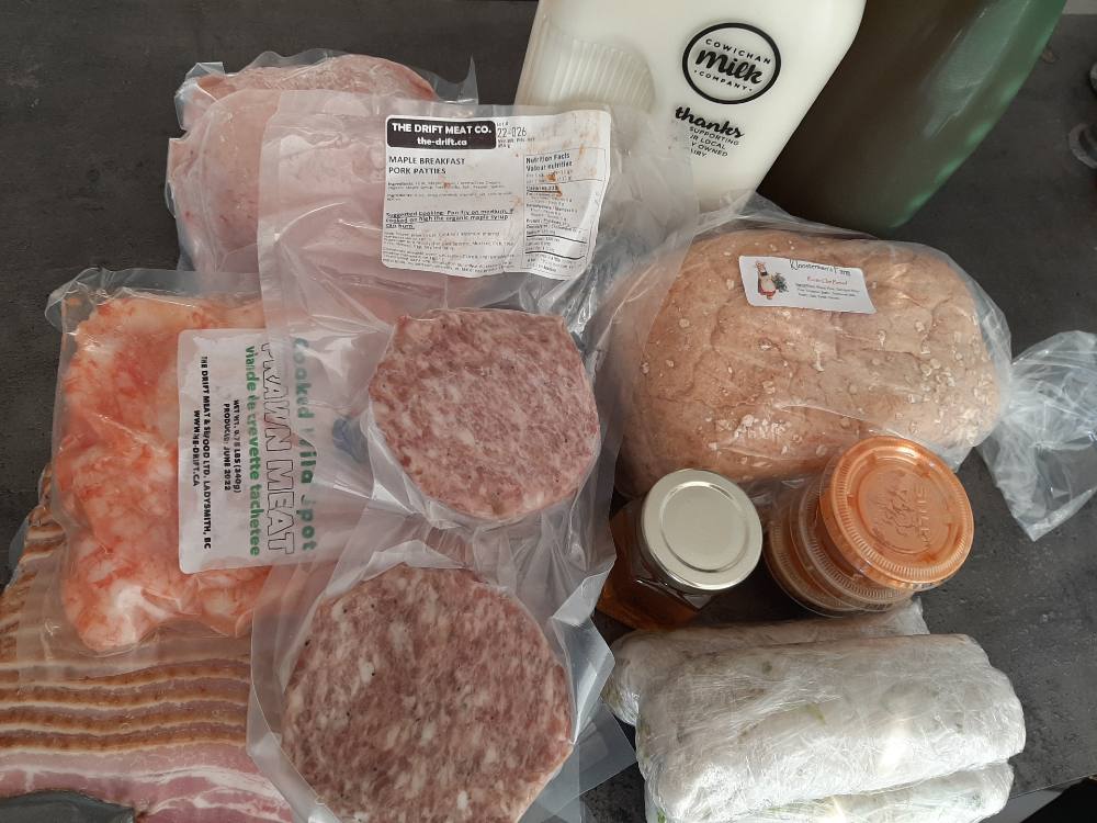 A bird&rsquo;s-eye view of a selection of groceries from the author&rsquo;s trip to the Cowichan Valley, including meats, milk and bread.