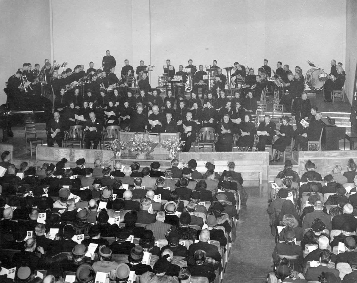 A black and white photo shows a big band playing on stage, from the audience&rsquo;s point of view. It&rsquo;s a packed house.