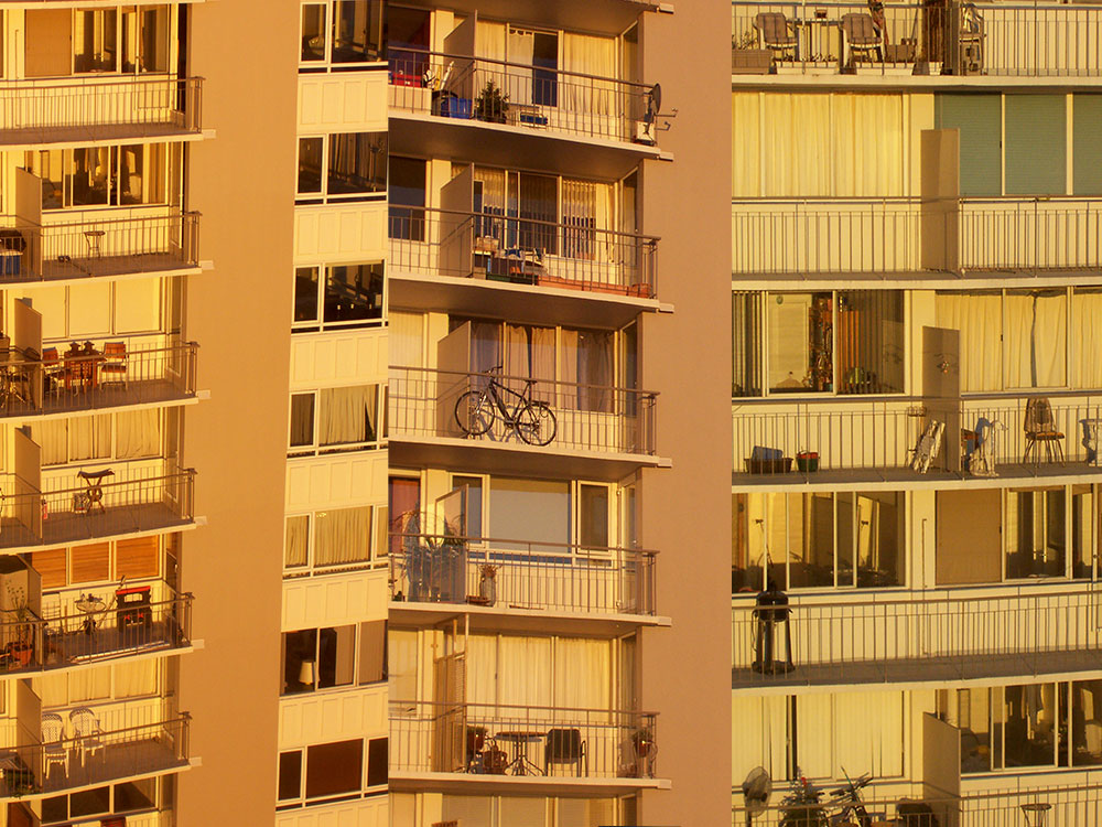 A triptych shows three older high rise buildings in the West End of Vancouver, at golden hour. 