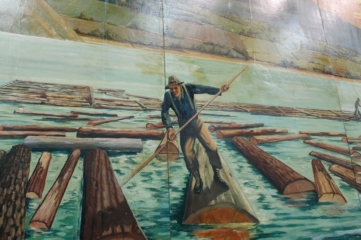 A mural closeup shows a log-driver working.