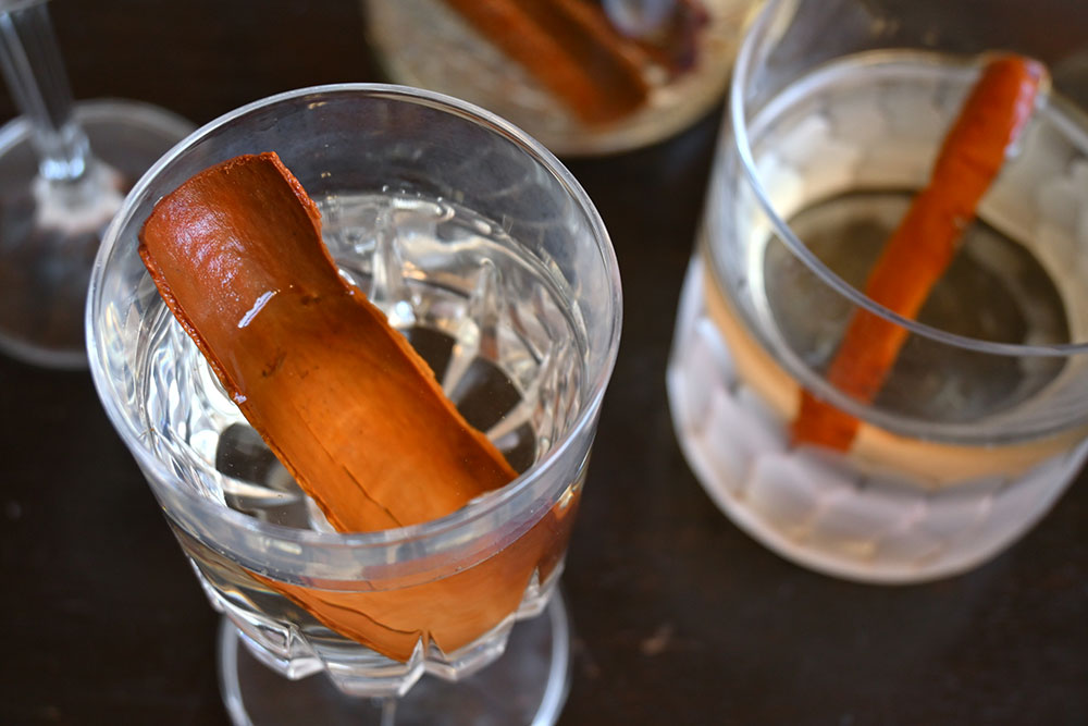 A few fancy whisky glasses filled with water. Each holds a cinnamon stick.