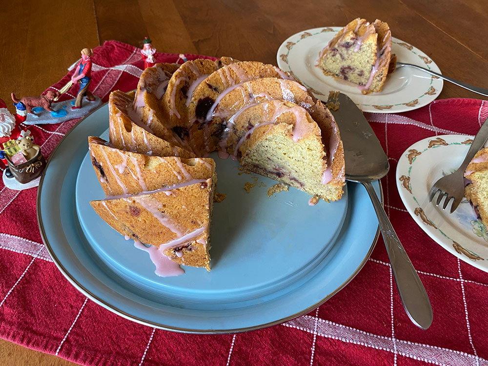A photo of a sliced Bundt cake, with two slices to the right. Christmas figurines appear on the left.