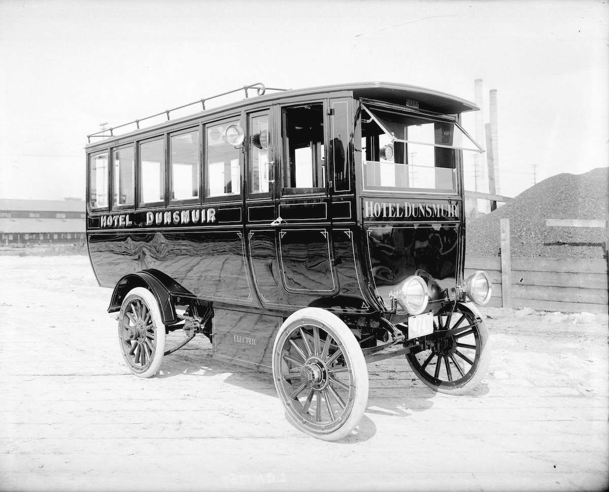 A shiny black electric trolley bus has been painted with the text 'Hotel Dunsmuir.'