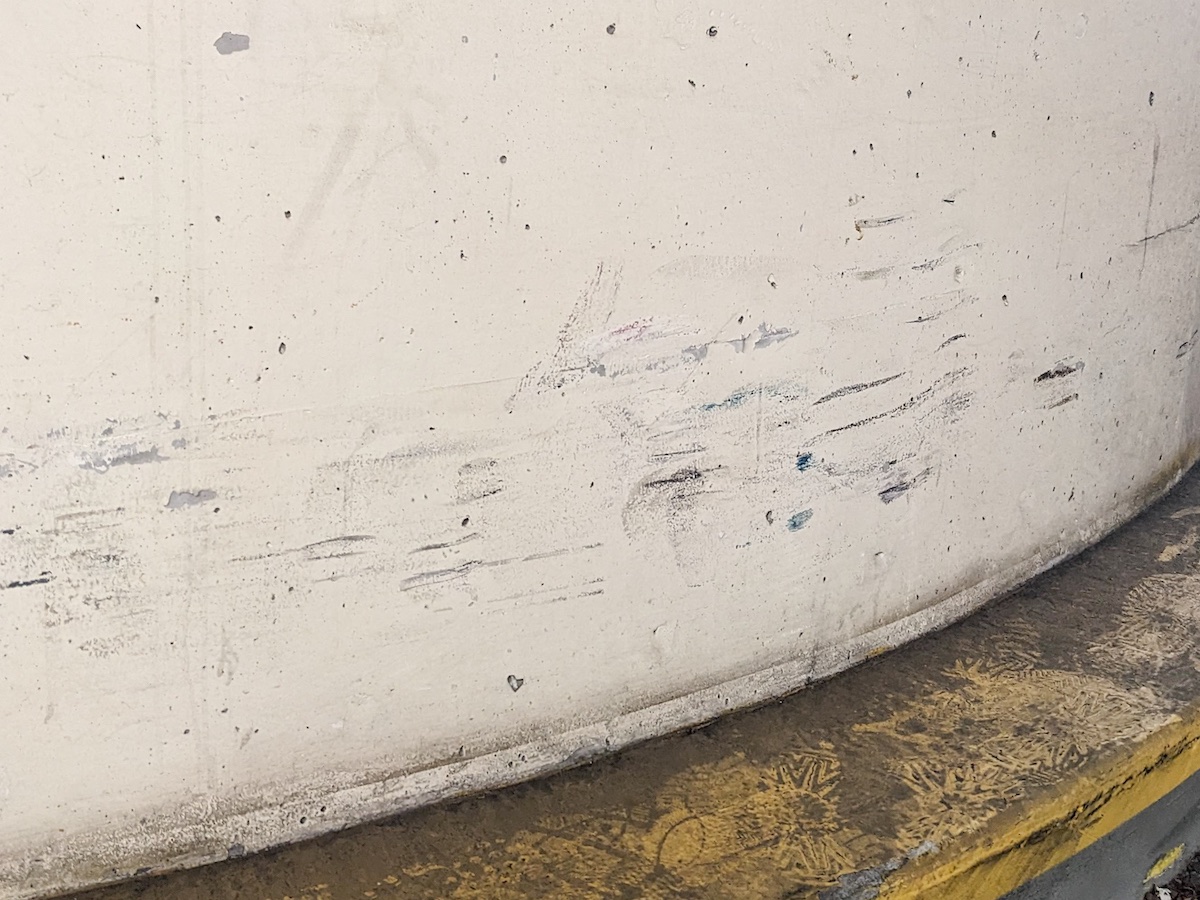Scrapes and scratches on a white cement wall.