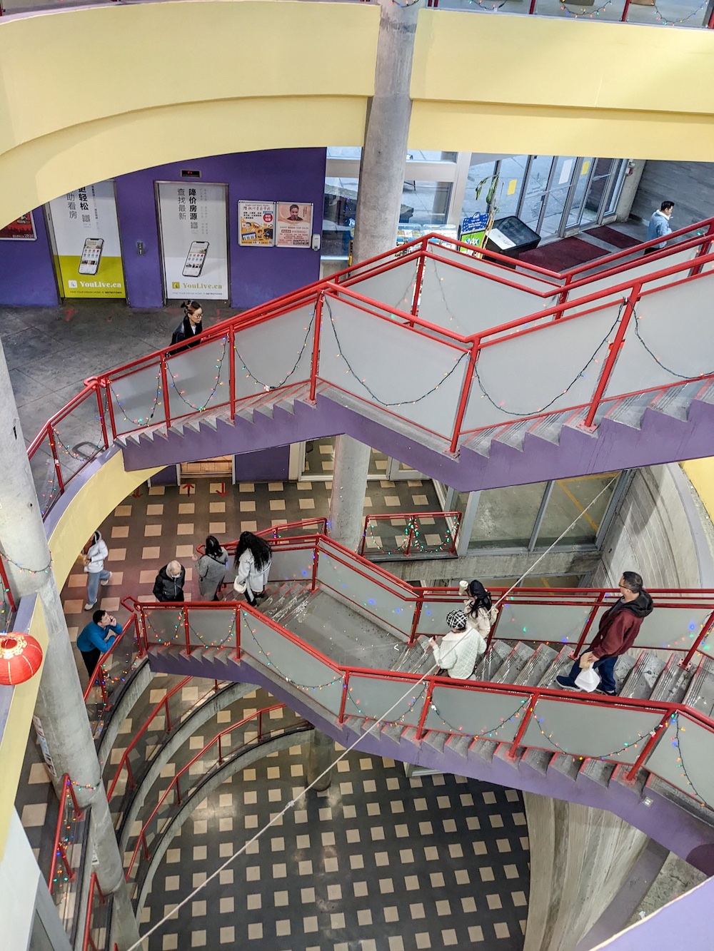 A vertical picture of the circular hole bored down through two levels of shopping and four levels of parking. The hollow is crossed by flights of stairs.