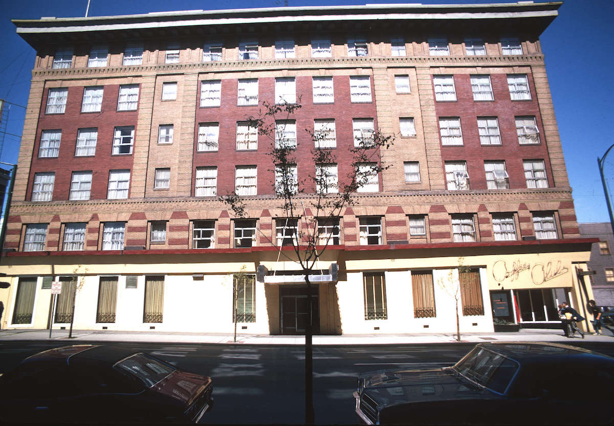 A wide, five-storey brick building. On the ground level is a shop called the Coffee Club.