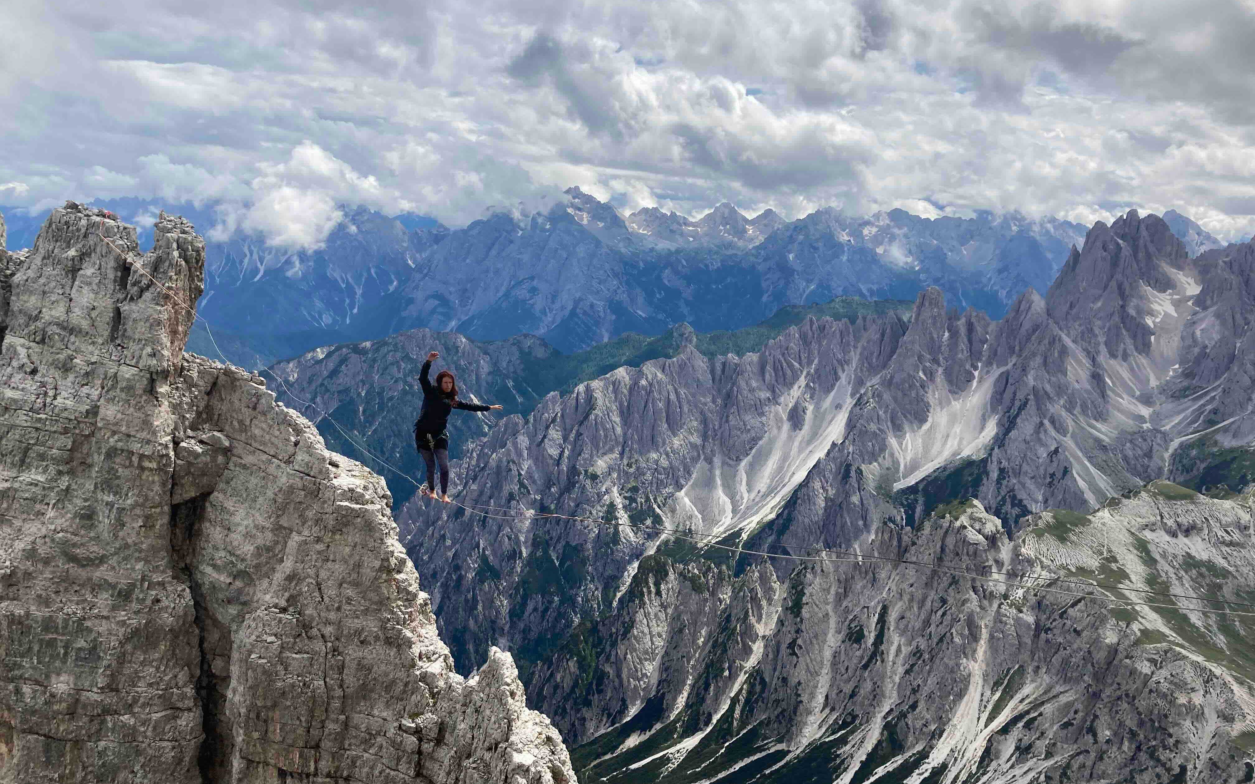 A woman high lines between snowy peaks.