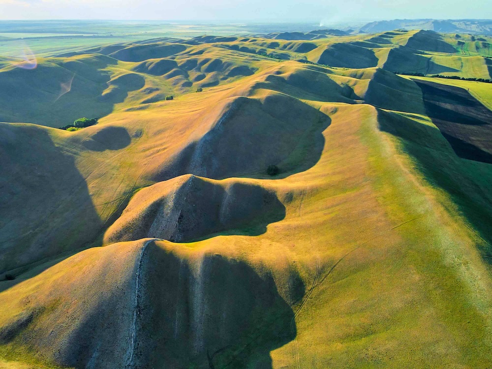 An aerial view of a green mountain range extends to the far horizon.