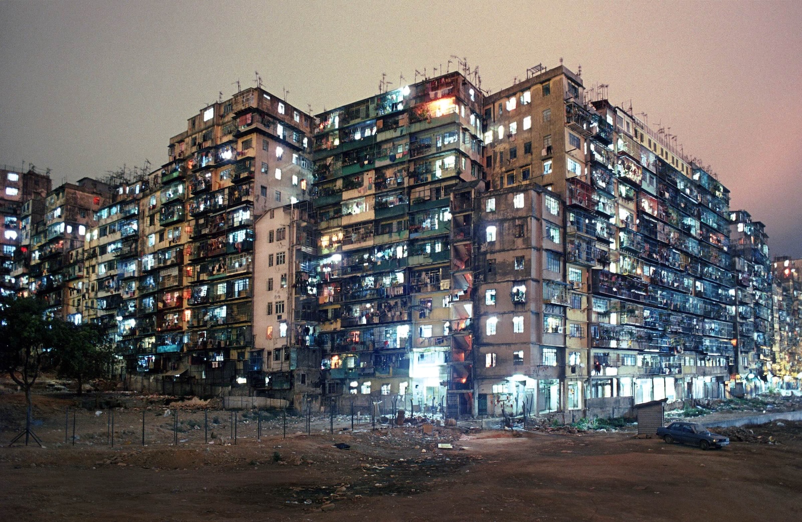 A large bank of wide highrise apartment buildings at night; the windows glow from indoor lights.