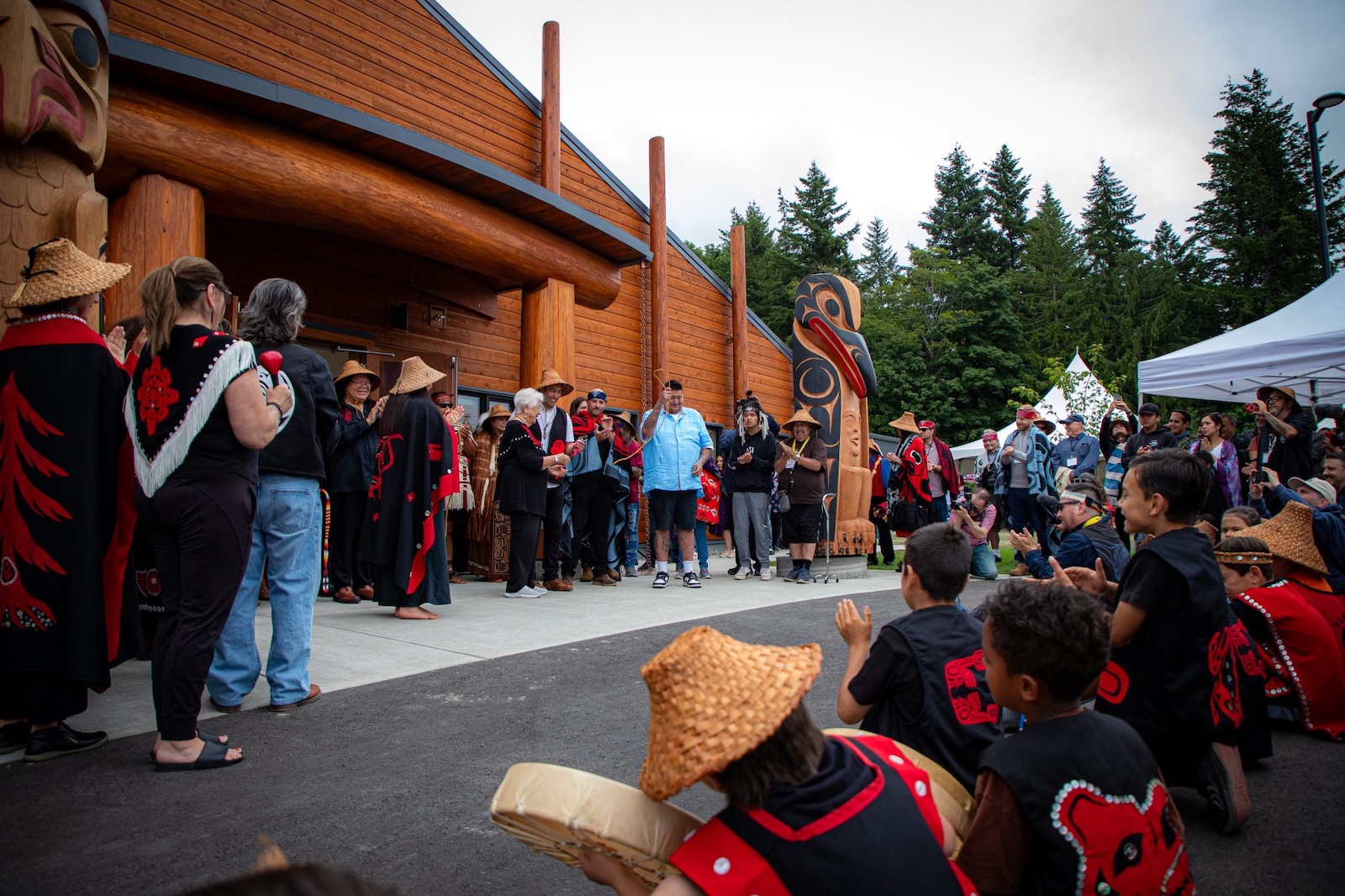 People gather outside a large wooden building at a ceremony to mark the opening of a new cultural centre in Tla&rsquo;amin territory.