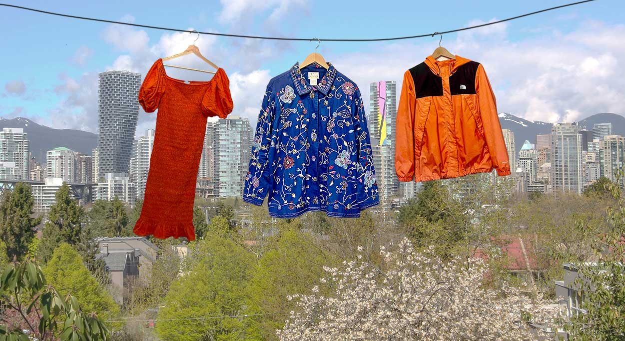 A cityscape of Vancouver features with an illustrated clothesline in the foreground and three clothing items hanging across: an orange-red dress, a blue floral fall coat and an orange and black North Face windbreaker. 