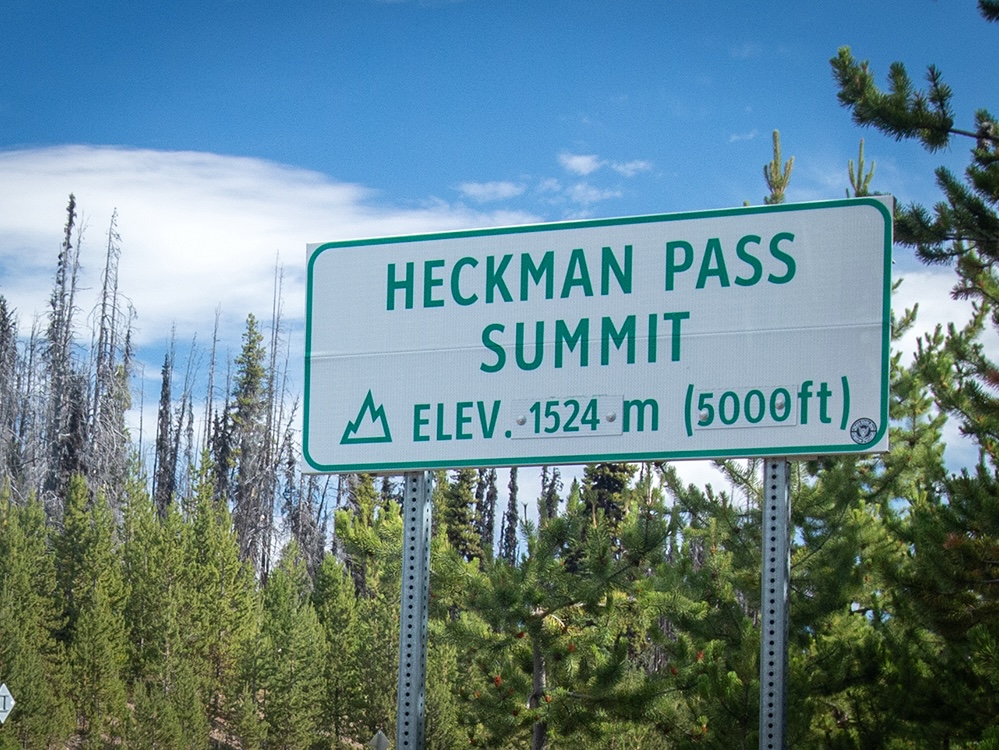 A white road sign with green lettering that says &lsquo;Heckman Pass Summit elevation 1,524 metres.&rsquo;