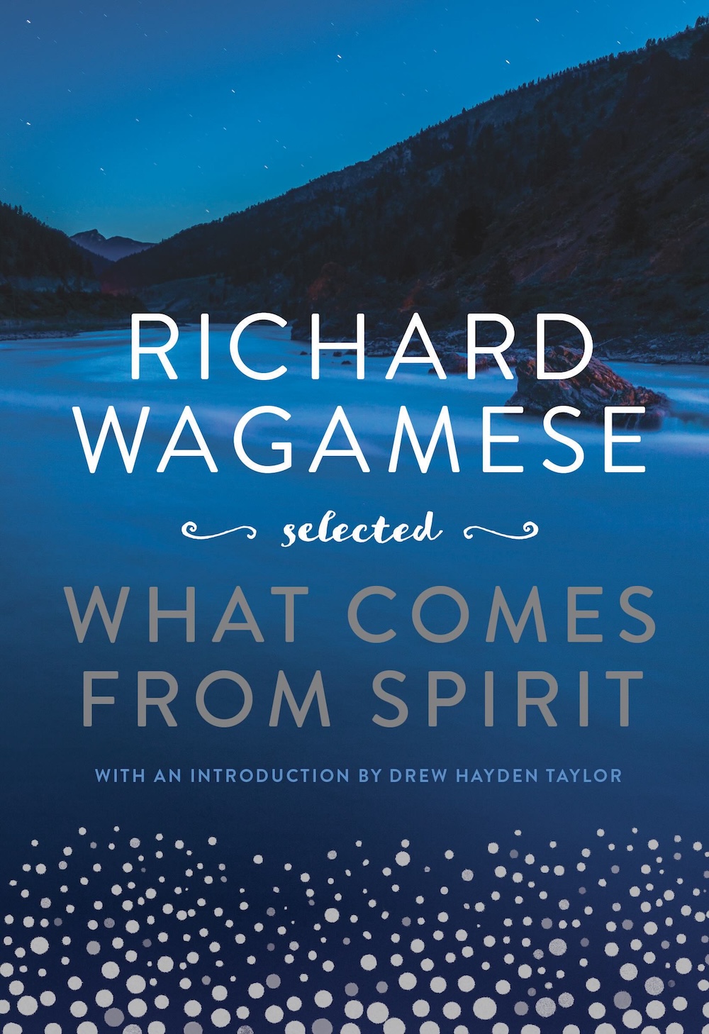 The book cover image for &lsquo;Richard Wagamese Selected: What Comes from Spirit&rsquo; features white and silver title text against a blue background featuring water against dark mountains and a blue sky. Digital silver dots are assembled at the bottom of the frame.
