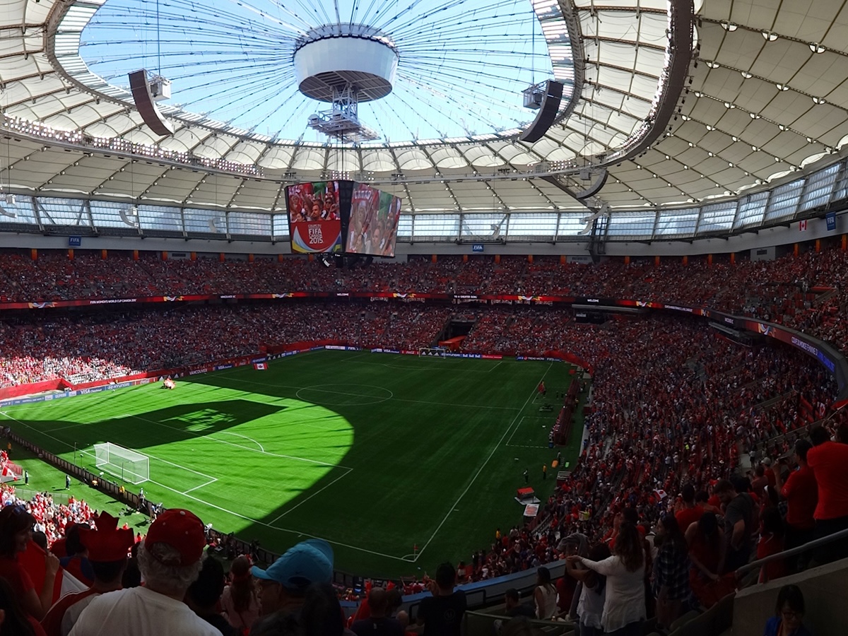People in Canada jerseys gather in BC Place to watch a soccer game.