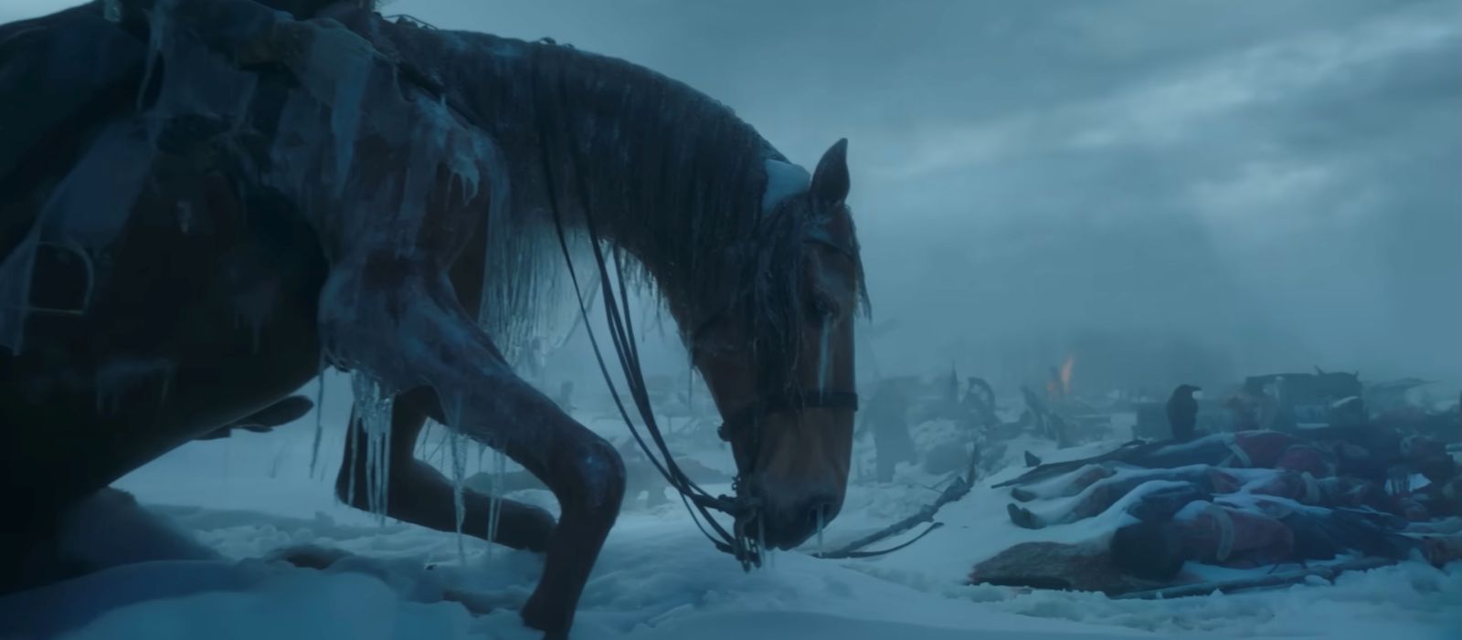 A frozen horse mid-step stands in snow littered with debris in fading light.