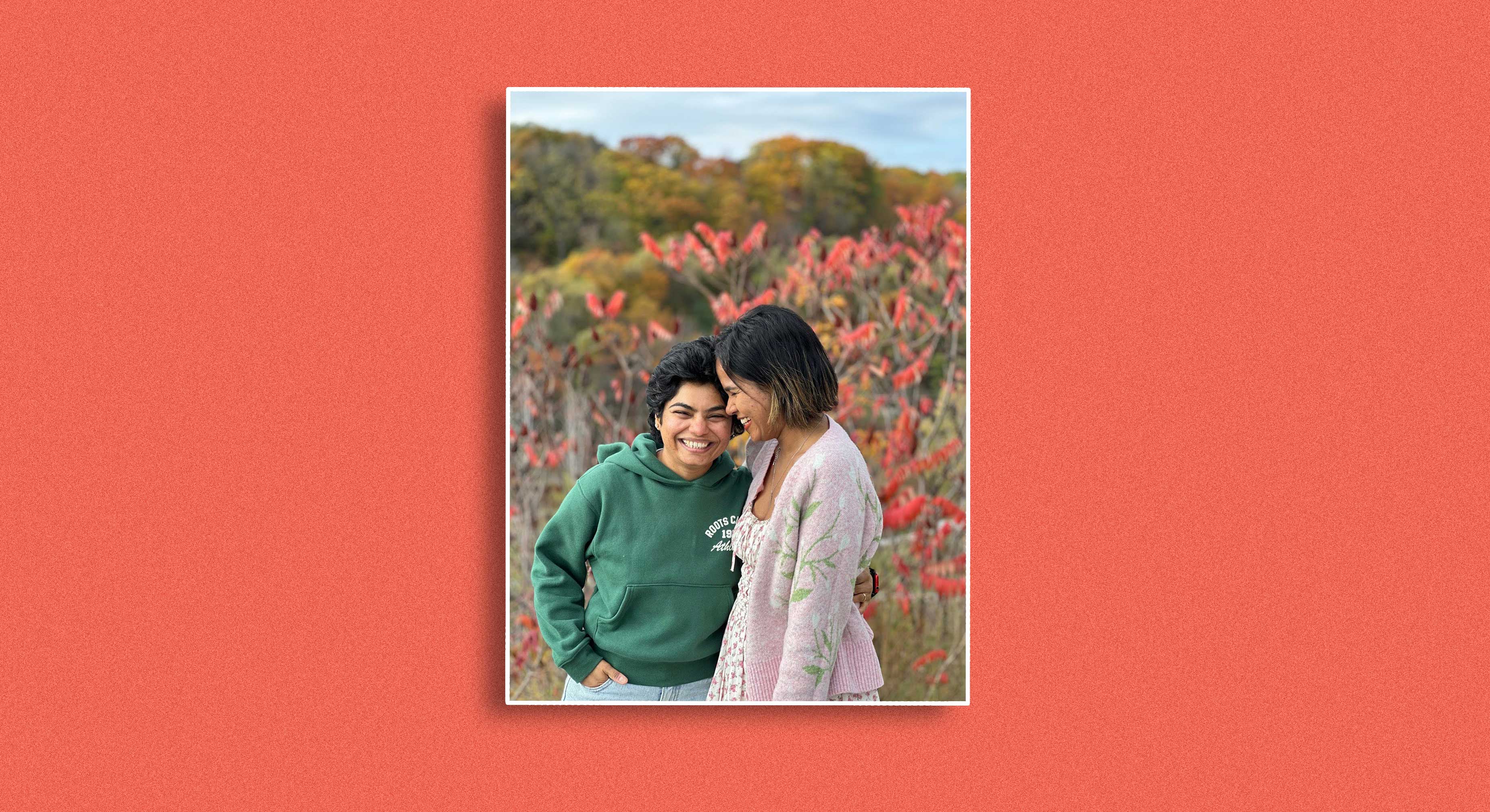 Shubhalaxmi Patil, at right, with her wife Dharti, at left, stand outdoors together, smiling. It&rsquo;s a bright fall day, and there are plants with red leaves in the background.
