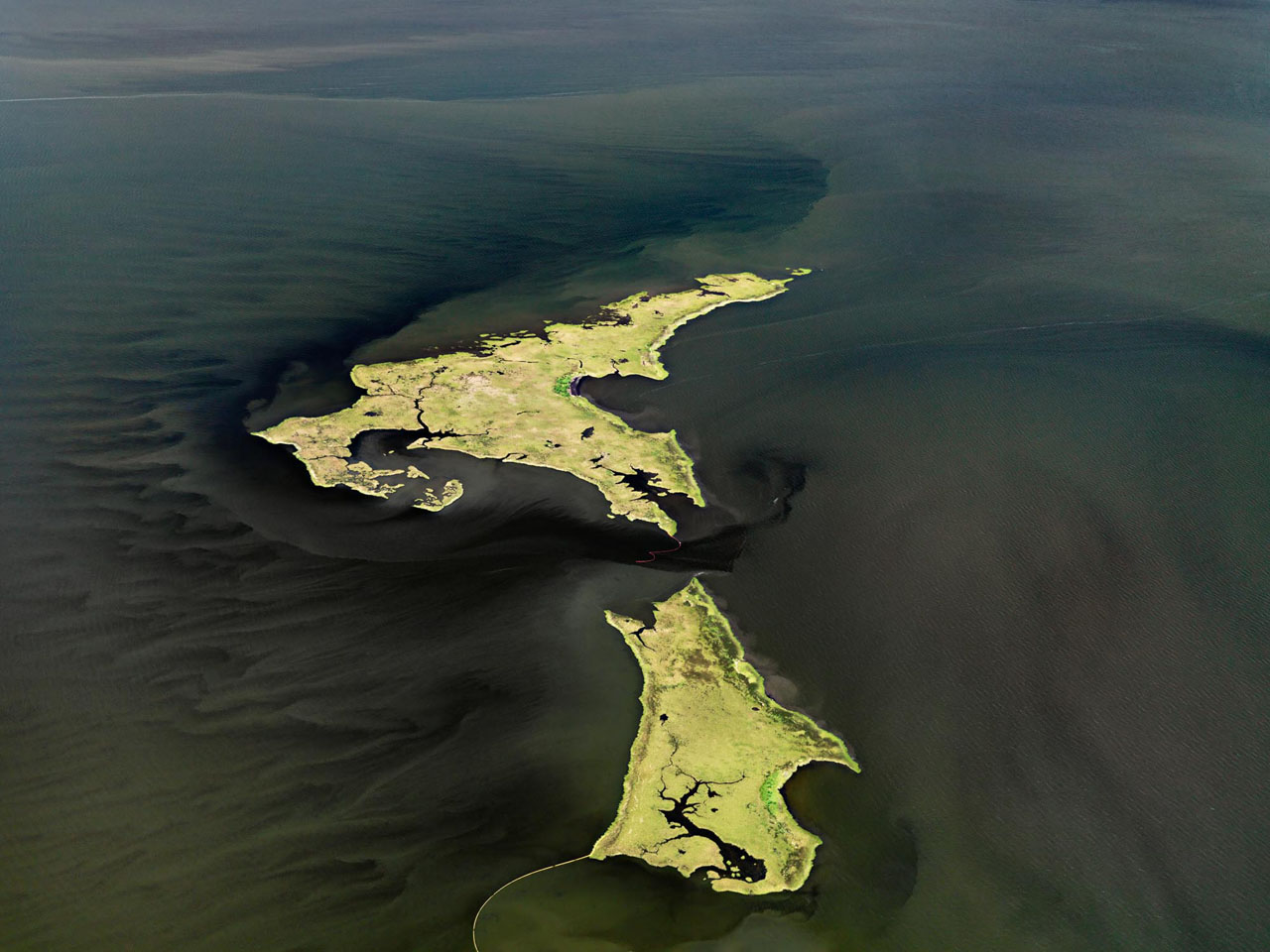 A bird&rsquo;s eye view of part of the Gulf of Mexico features darkened waters against the sharp relief of bright yellow island-like shapes.  