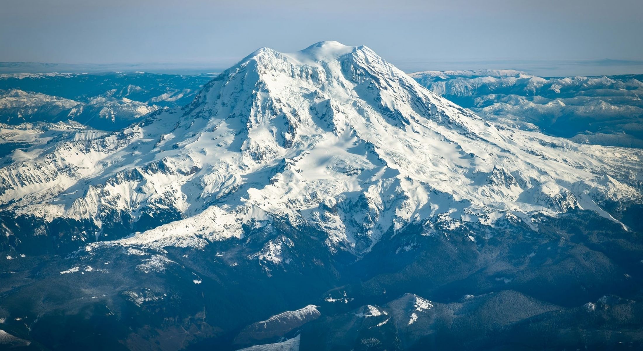 A snowy mountain range against a blue sky.